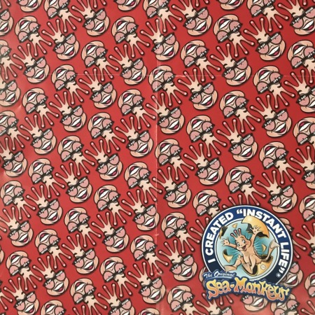 Wrapping Paper Side: Pattern of a Sea-Monkey head wearing X-Ray Spex.